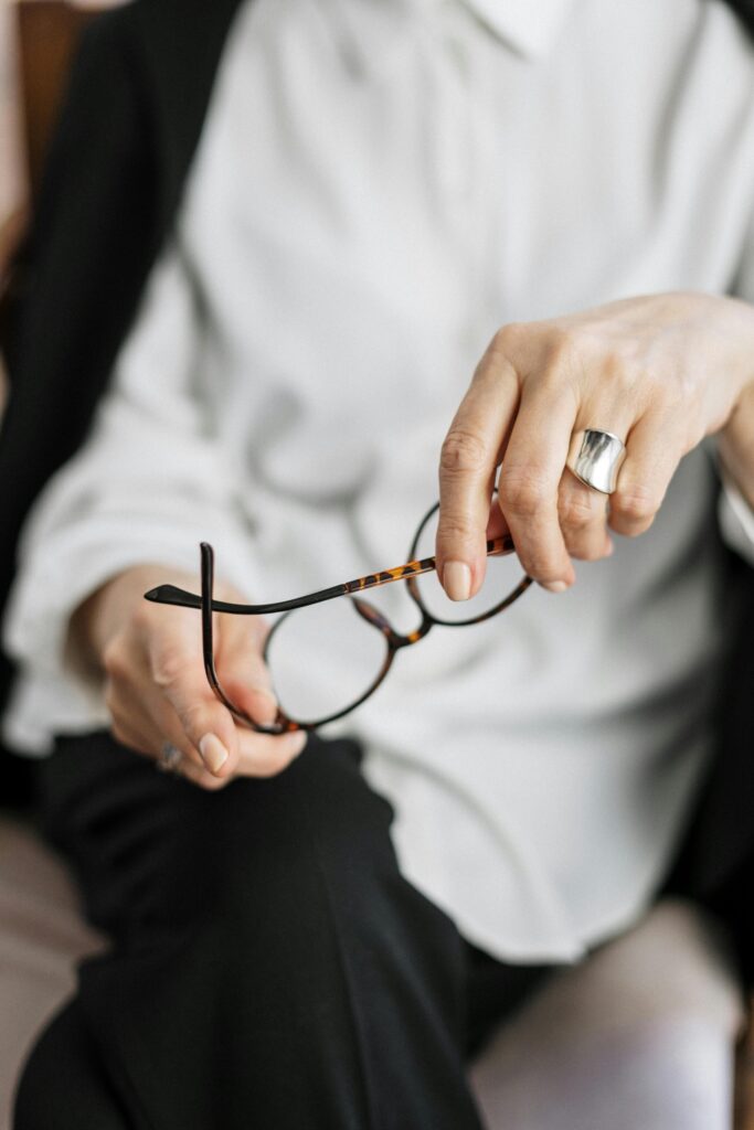 pexels-photo-4098340-4098340 Close-up of a woman holding glasses, symbolizing thought and professionalism.